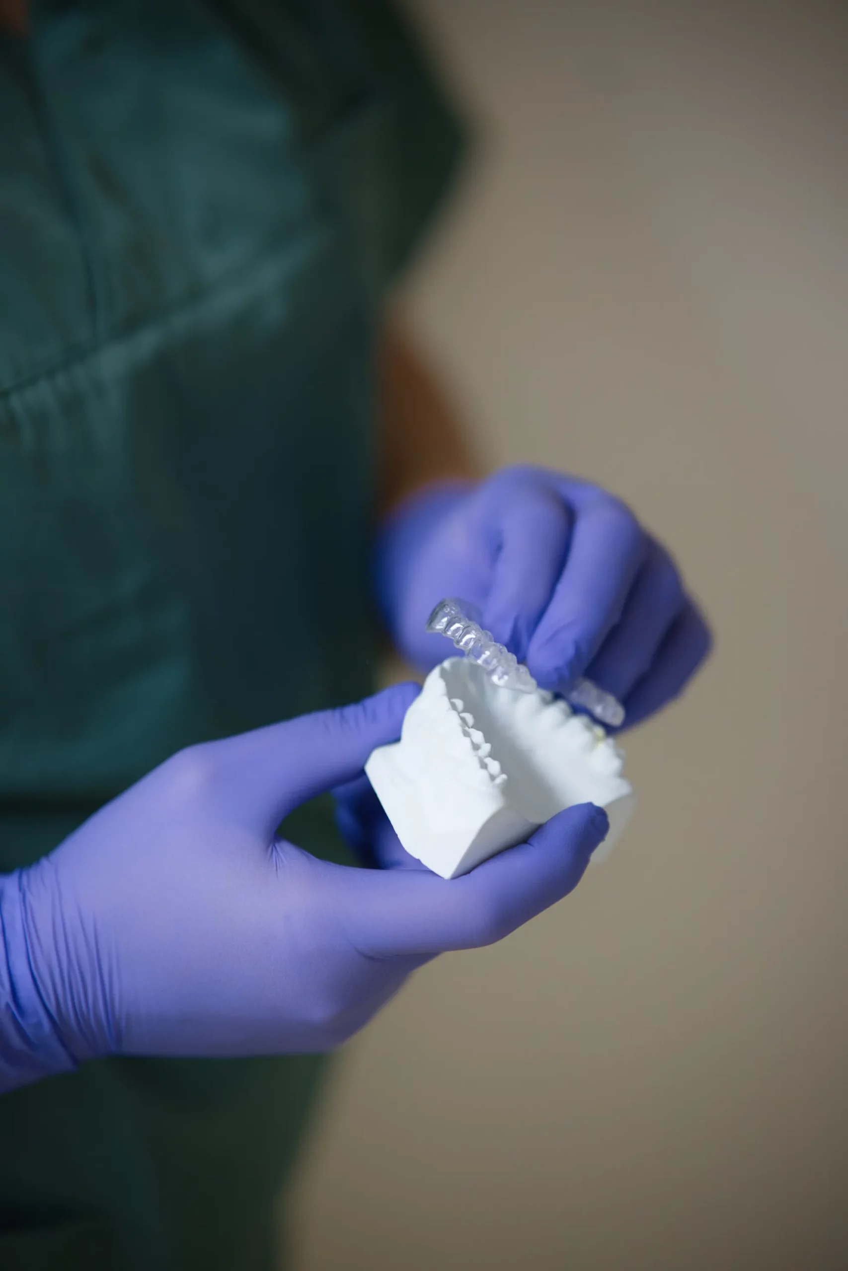 Hände mit Handschuhen halten ein Gipsgebissmodell mit einer Schiene