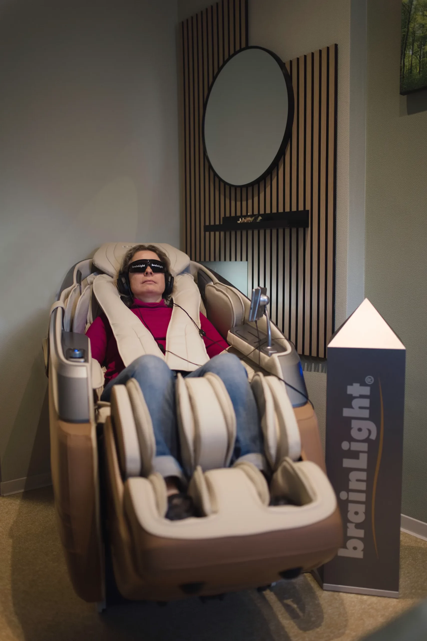 Person mit Brille und Kopfhörern im brainLight Massagestuhl