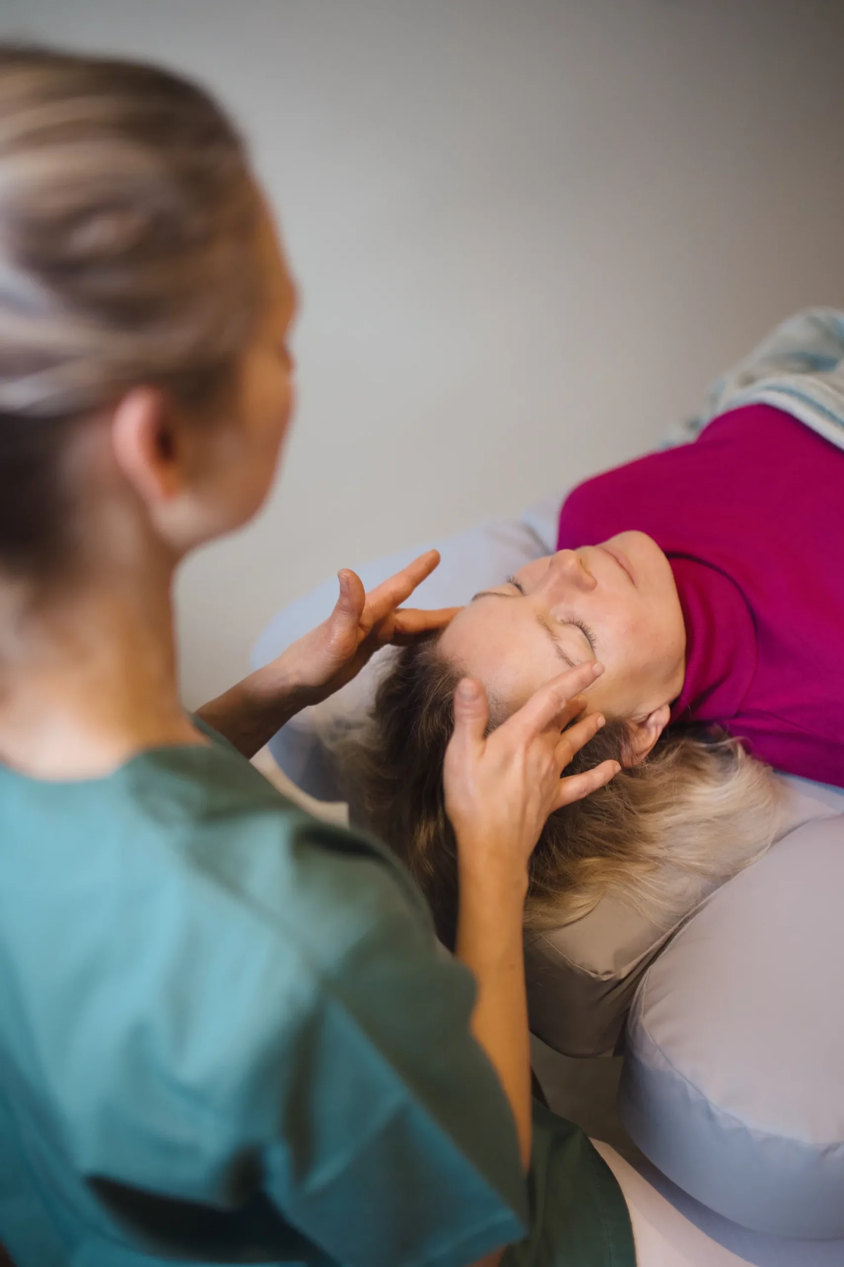 Patientin auf der Liege wird von der Mitarbetierin am Kopf massiert