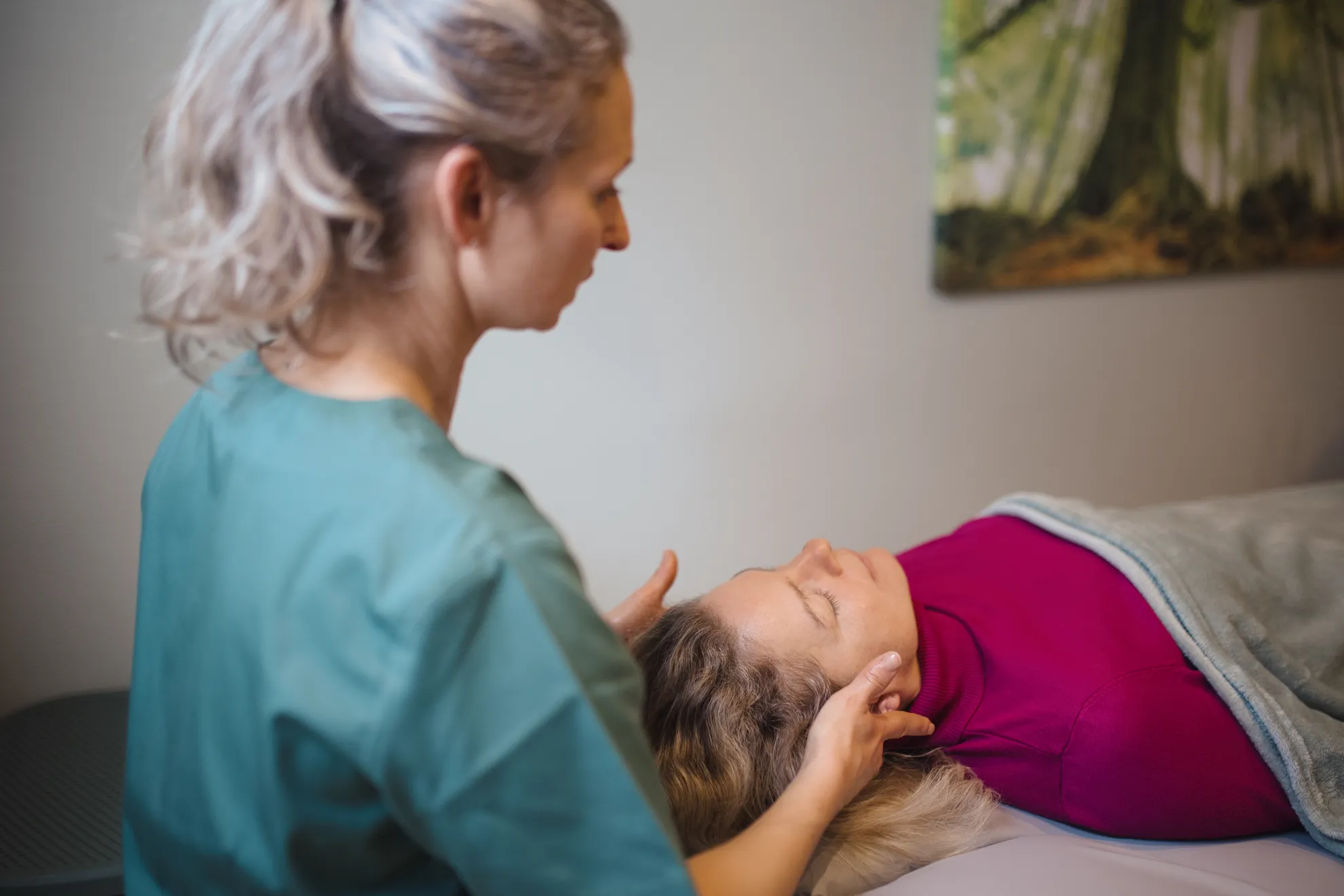 Patientin auf der Liege wird von der Mitarbetierin am Kopf massiert